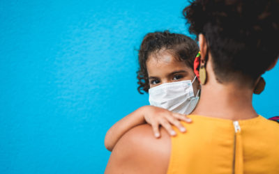 a mom holds a little girl wearing a mask